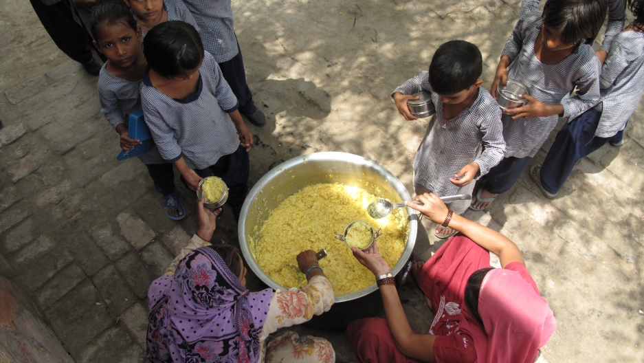 Santosh (left) and Suman (right), the two school cooks serve the khichdi to girls during lunch time. Santosh (left) and Suman (right), the two school cooks serve the khichdi to girls during lunch time.